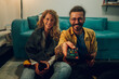 © Zamrznuti tonovi - Smiling couple sitting on the floor in front of the TV while enjoying wine.