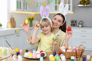 Sticker - Mother and her cute son with Easter eggs at table in kitchen