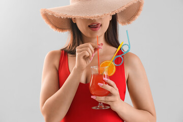 Sticker - Young woman in summer hat with cocktail on light background