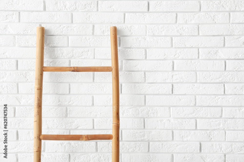 Wooden ladder near white brick wall in room