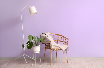 Armchair, lamp and houseplant near lilac wall