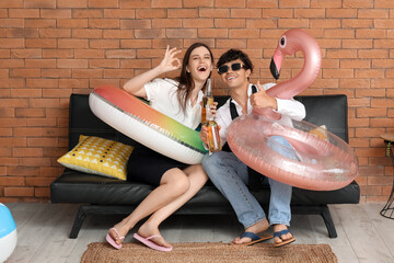 Canvas Print - Young couple with beer and swim rings ready for summer vacation in office