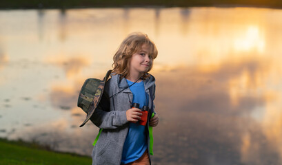 Scout boy wearing explorer hat and backpack outdoor. Explorer and adventure with binocular.