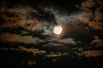 Wall Mural - The full moon is surrounded by dramatic colored clouds in the dark night sky. HDR photo taken through a telephoto lens