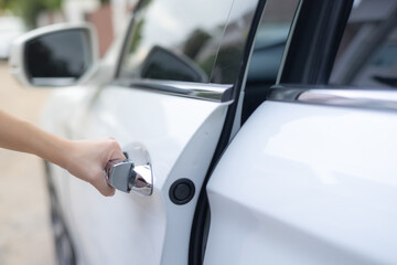 Wall Mural - Close-up of a female hand opening a white car door. Automotive concept. opening doors, concept cars, driving safely. theft concept.