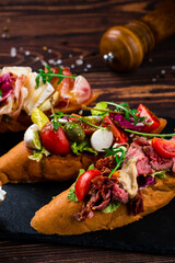 Canvas Print - Italian food bruschetta with beef slices, capers, cherry tomatoes, mozzarella, salmon, cucumber, lettuce.