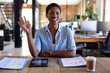 © Wavebreak Media - Portrait of happy african american casual businesswoman having video call and waving hand in office