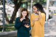 © NINENII - Portrait of two stylish pretty women standing and holding tablet, women speak with remote clients using phone. working concept lifestyle.