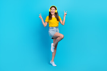 Wall Mural - Full size photo of pretty excited girl demonstrate v-sign enjoy listen music isolated on blue color background