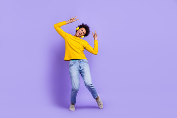 Full size photo of cool guy dressed yellow long sleeve headphones dancing having fun show v-sign isolated on purple color background