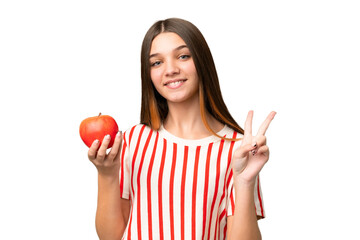 Poster - Teenager girl with an apple over isolated chroma key background smiling and showing victory sign