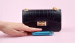 A blue bullet-dildo in a small black purse on a light background with copyspace text for a sex shop.