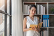 © Natee Meepian - Young attractive business woman work and holding a book in the office