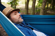 © baranq - Man taking a nap sleeping in hammock in forest during summer vacation