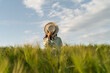 © RooM The Agency - Woman standing in a field covering her face with a straw hat, Belarus