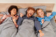 polyamory concept, three adults, man and interracial women in pajamas waking up together, morning, under blanket, bedroom, cultural diversity, bisexual, open relationship, polygamy, top view