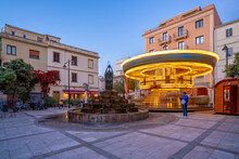 View Of Carousel And Fountain On Piazza Matteotti At Dusk, Olbia, Sardinia