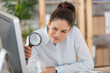 businesswoman examining a contract meticulously with a magnifying glass