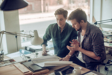 Two young men working on a project together in a startup company office