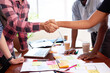 © Meeko Media - Close up of two tech engineers shaking hands at design launch meeting mobile app