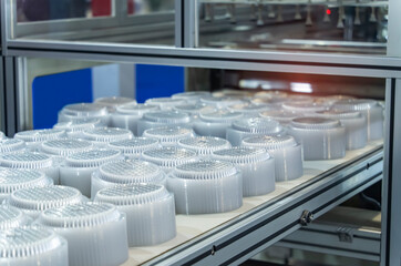 Stack of polypropylene food containers on conveyor belt of automatic plastic injection molding machine,automated technology concept