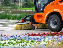 Sweeping Machine Brushes Clean The City Sidewalk. Summer City Background With Sweeper.