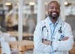 © Tshidzumba/peopleimages.com - Portrait, black man and happy doctor with arms crossed in hospital for healthcare. African medical professional, face and surgeon, person or confident employee from Nigeria with smile for wellness.