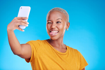 Sticker - Social media, selfie and funny face with a black woman on blue background in studio to update her profile picture. Post, app and a happy young female influencer taking a photograph for her status