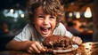 © JMarques - Happy, smiling child eating a chocolate cake with melted chocolate on top on a wooden table.