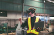 © amorn - Male factory mechanic using virtual reality headset. Male engineer working or using virtual reality headset for checking machinery in industry factory and wearing safety uniform and helmet