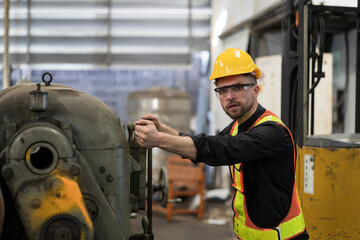 Male engineer worker working and inspecting parts quality of lathe machine in industry factory, wearing safety uniform, helmet. Male technician worker maintenance parts of machine in workshop