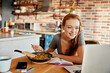 © Geber86 - Young woman using a laptop while having breakfast in the morning