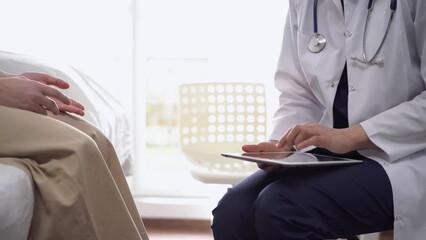 Wall Mural - Doctor and patient sitting opposite each other in clinic, closeup. Unknown female physician using tablet computer. Medicine concept