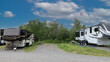Rv trailers parked at campsite side by side with bikes and trees and a bench