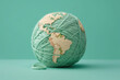 Soft Earth globe made of ball of yarn on pastel green background. Generative AI