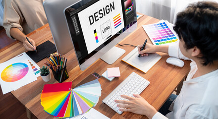 Poster - Graphic designer work on computer laptop and with graphic drawing pen while brainstorming unique design with professional graphic team in modern digital studio workplace. Panorama shot. Scrutinize