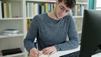 Wall Mural - Young hispanic man student using computer taking notes at library university