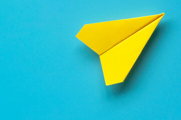 Wall Mural - Top view of yellow paper airplane on blue background with customizable space for text