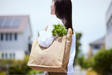 団地を歩く買い物バッグを持った主婦の日本人女性