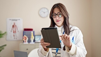 Poster - Young beautiful hispanic woman doctor using touchpad working at clinic