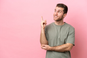 Wall Mural - Young caucasian man isolated on pink background pointing up a great idea