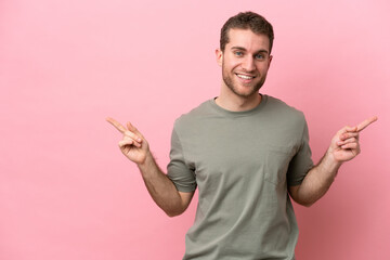 Poster - Young caucasian man isolated on pink background pointing finger to the laterals and happy