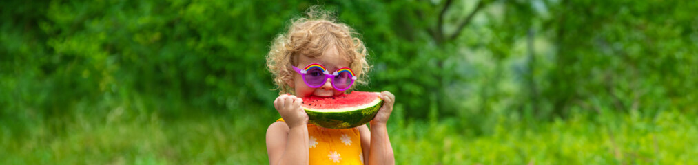 Poster - A child eats watermelon in the park. Selective focus.