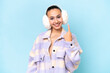 Young Arab woman wearing winter muffs isolated on blue background pointing with the index finger a great idea