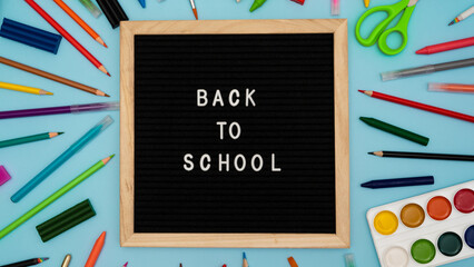 Text: Back to school soon on a wooden letter board. buying stationery, flatlay, bright background. Autumn school fees. photo 16:9