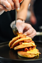 Poster - woman chef hand cooking pancakes with meat, bacon and cheese sauce