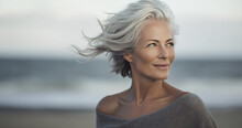 Portrait Of A Senior Woman In Her 50s With Grey Flowing Hair On A Beach Background