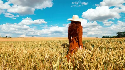 Sticker - Stylish redhead woman in red dress with suicase in wheat field with clouds in blue sky on background