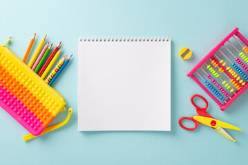 Explore the wonders of early education with this top-down perspective: a vivid assortment of school supplies on a pastel blue surface, providing blank album page as copyspace for text or advertising