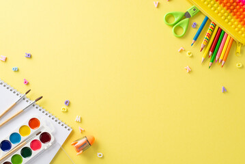 Get inspired by the world of art education with this captivating top-down image: an album, watercolor paints, and vibrant stationery on a yellow backdrop, perfect for advertising or text messages